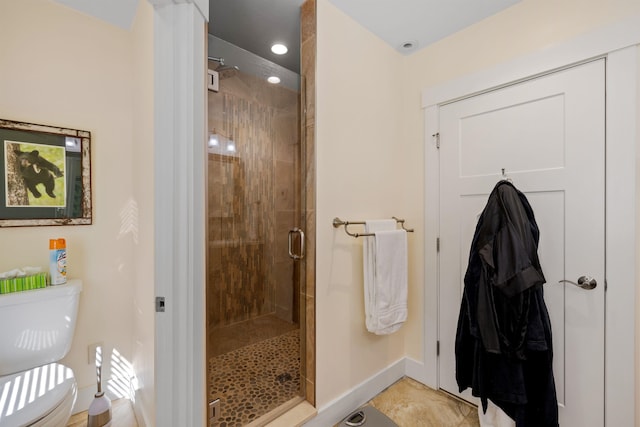 bathroom featuring toilet and a shower with shower door