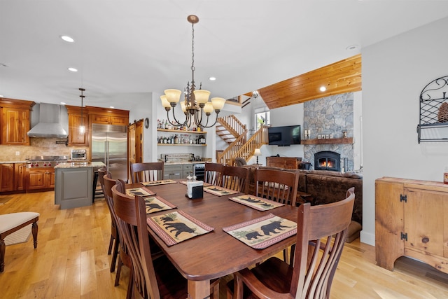 dining room with a notable chandelier, light hardwood / wood-style floors, and a stone fireplace