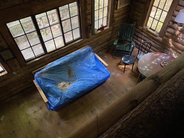 living area with rustic walls, plenty of natural light, and wood-type flooring