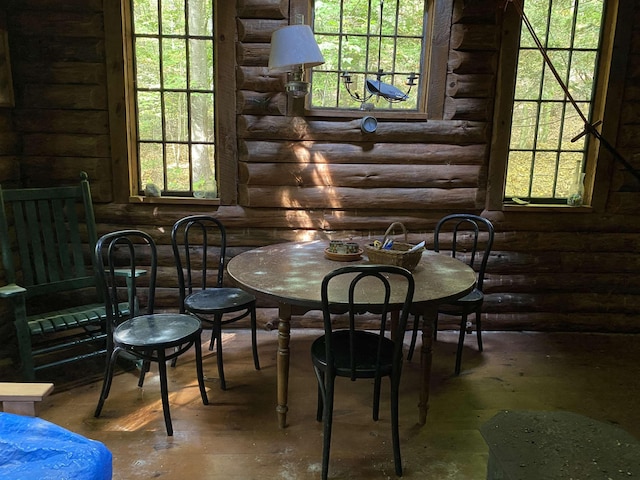 dining area featuring a healthy amount of sunlight and log walls