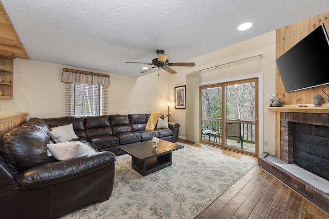 living room featuring plenty of natural light, hardwood / wood-style floors, a textured ceiling, and a brick fireplace