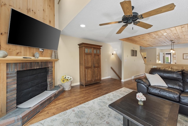 living room with dark hardwood / wood-style flooring, ceiling fan, a baseboard radiator, wooden ceiling, and a fireplace