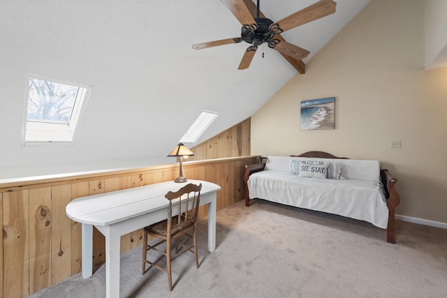 bedroom featuring vaulted ceiling with skylight, ceiling fan, light colored carpet, and wooden walls