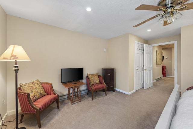 sitting room featuring ceiling fan, light colored carpet, a baseboard radiator, and a textured ceiling