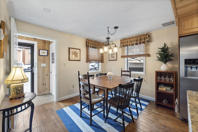 dining room featuring a textured ceiling, a chandelier, and dark hardwood / wood-style floors