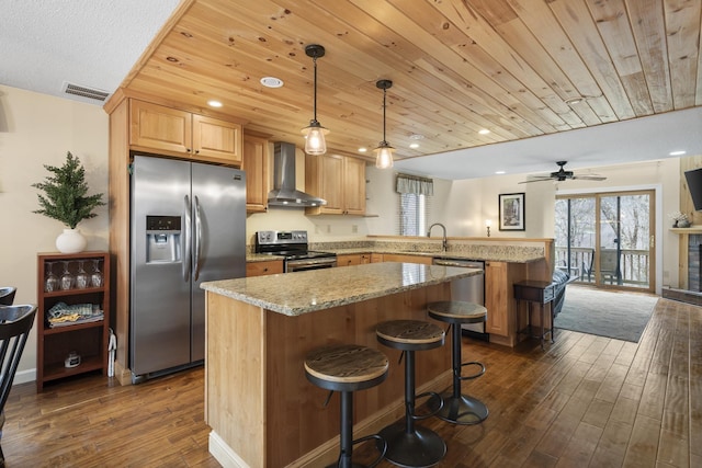 kitchen featuring pendant lighting, wall chimney exhaust hood, dark hardwood / wood-style floors, kitchen peninsula, and stainless steel appliances