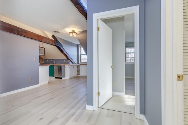 corridor featuring sink, light hardwood / wood-style floors, and beam ceiling