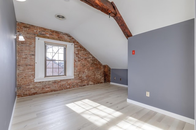 additional living space featuring brick wall, light hardwood / wood-style floors, and lofted ceiling with beams