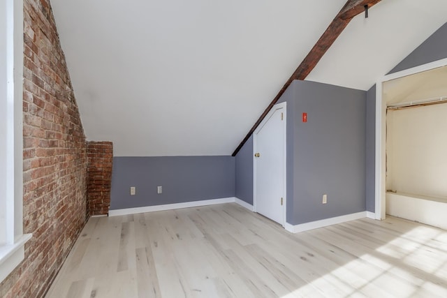 additional living space featuring light hardwood / wood-style flooring, vaulted ceiling with beams, and brick wall