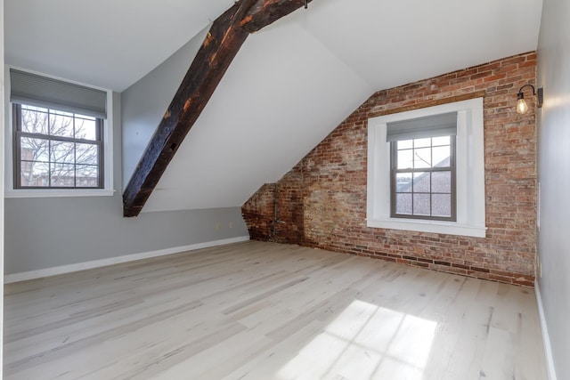 bonus room with light hardwood / wood-style flooring, vaulted ceiling with beams, and brick wall