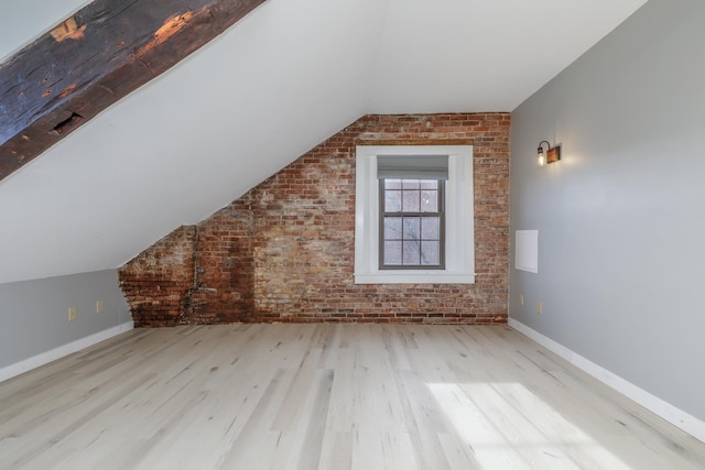 additional living space with light hardwood / wood-style flooring, vaulted ceiling, and brick wall