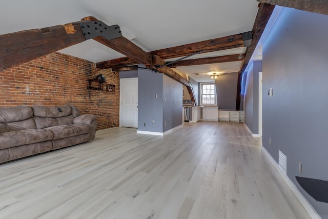 unfurnished living room featuring brick wall, light hardwood / wood-style floors, and beam ceiling