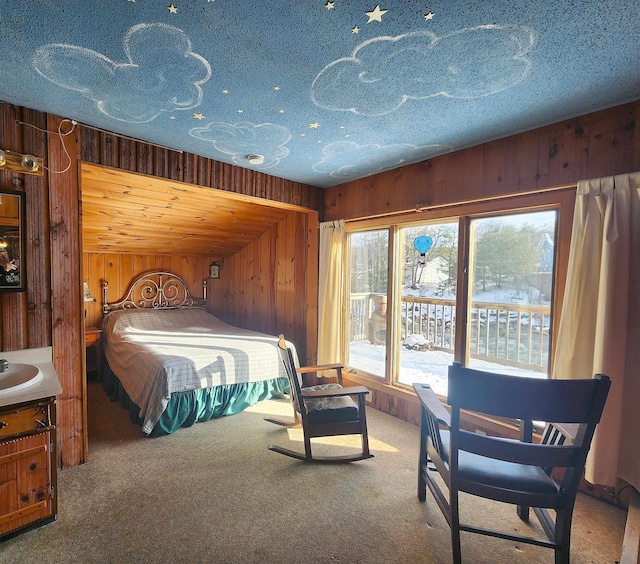 bedroom with access to exterior, wooden walls, carpet floors, and a textured ceiling