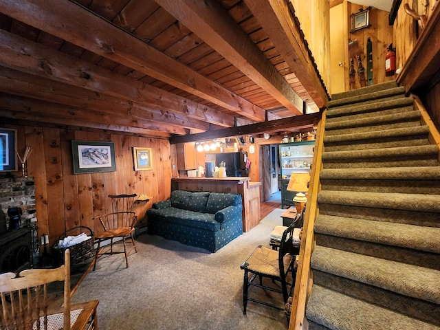 living room featuring wood walls, beam ceiling, carpet floors, and wooden ceiling