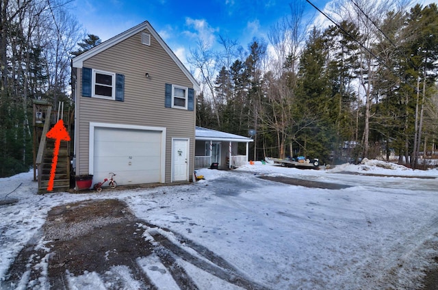 view of snow covered exterior featuring a porch and a garage