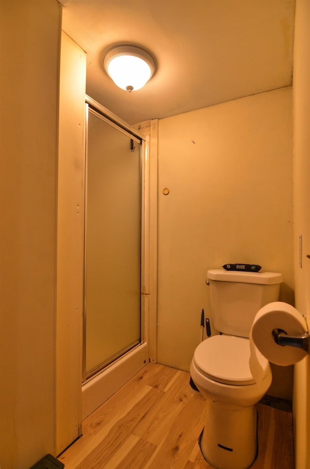 bathroom featuring hardwood / wood-style floors, toilet, and a shower with shower door
