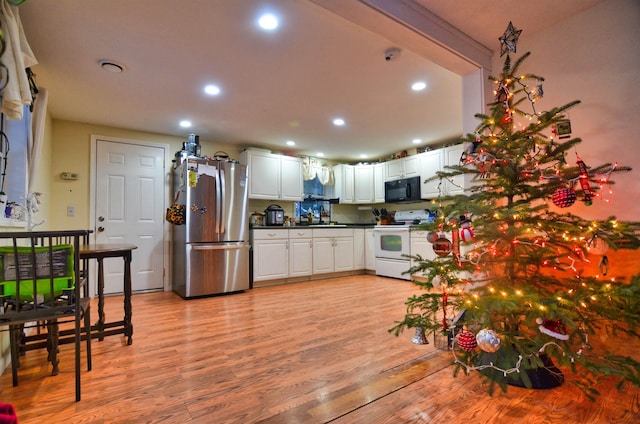 kitchen featuring stainless steel refrigerator, white cabinetry, sink, white range with electric stovetop, and light hardwood / wood-style floors