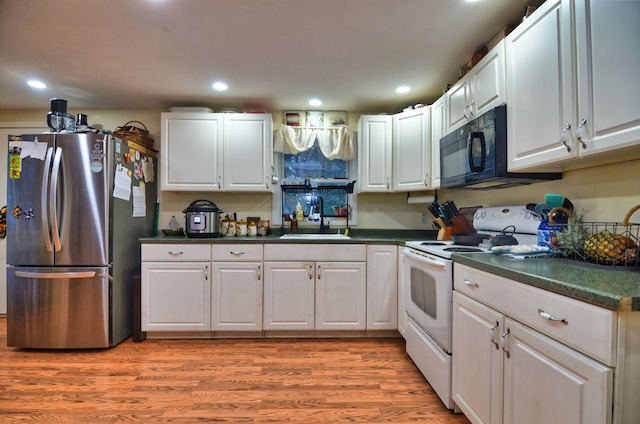 kitchen featuring stainless steel refrigerator, white cabinetry, and electric stove