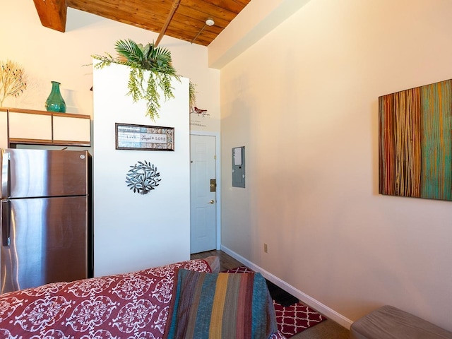 kitchen featuring wood ceiling, lofted ceiling with beams, white cabinets, electric panel, and stainless steel refrigerator