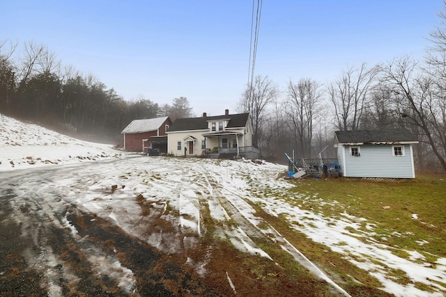 snow covered back of property featuring a shed