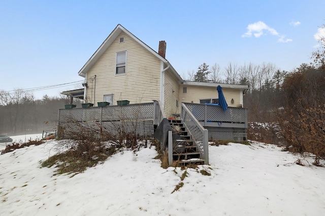 snow covered back of property featuring a wooden deck