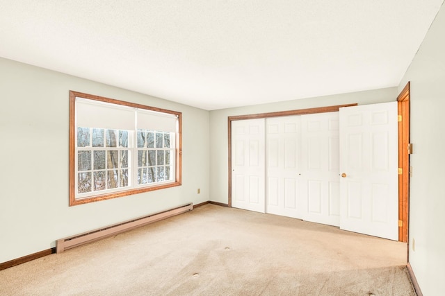 unfurnished bedroom with a closet, light colored carpet, and a baseboard heating unit