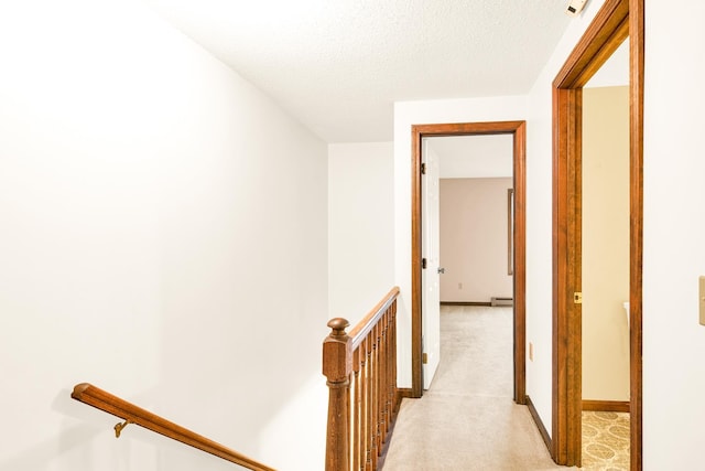 hallway featuring a textured ceiling, light colored carpet, and baseboard heating