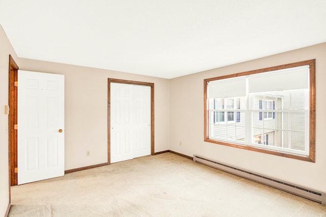 unfurnished bedroom with a closet, light carpet, and a baseboard heating unit