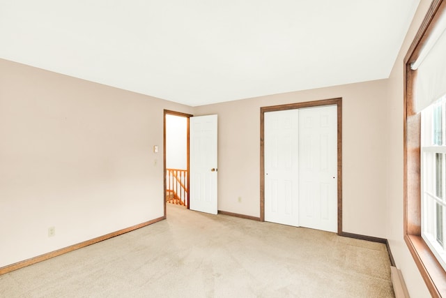 unfurnished bedroom featuring light carpet and a closet