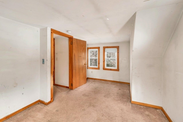 carpeted spare room with vaulted ceiling