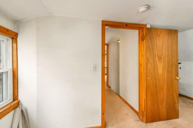 corridor featuring vaulted ceiling and light colored carpet