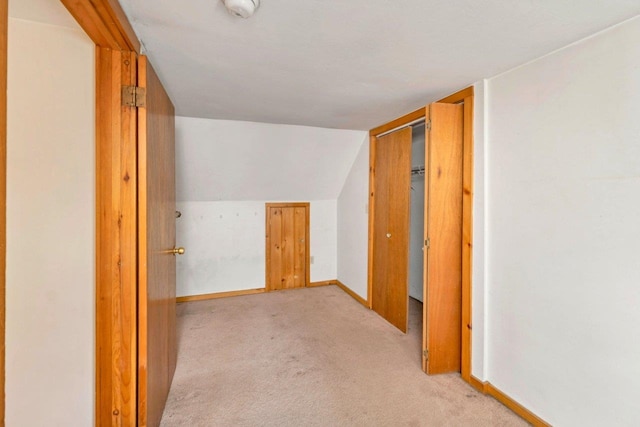 hallway with vaulted ceiling and light colored carpet