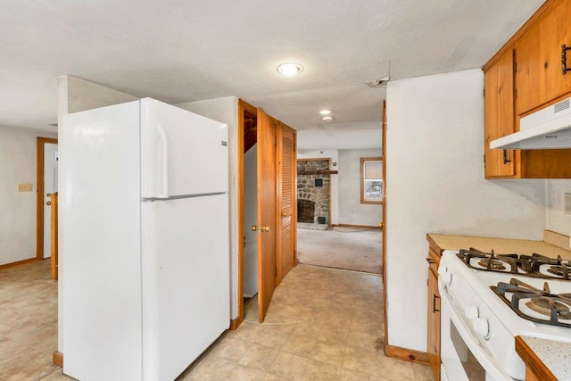 kitchen with white appliances, a fireplace, and ventilation hood