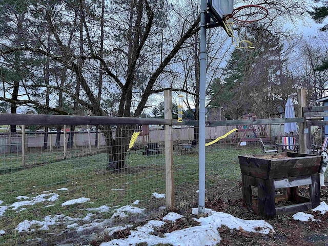 snowy yard featuring a playground