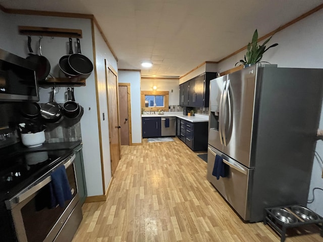 kitchen with appliances with stainless steel finishes, backsplash, crown molding, sink, and light hardwood / wood-style flooring