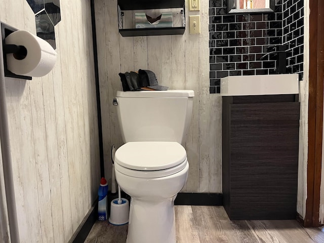 bathroom with wood walls, toilet, and wood-type flooring