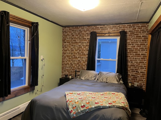 bedroom featuring a textured ceiling, crown molding, a baseboard heating unit, and brick wall