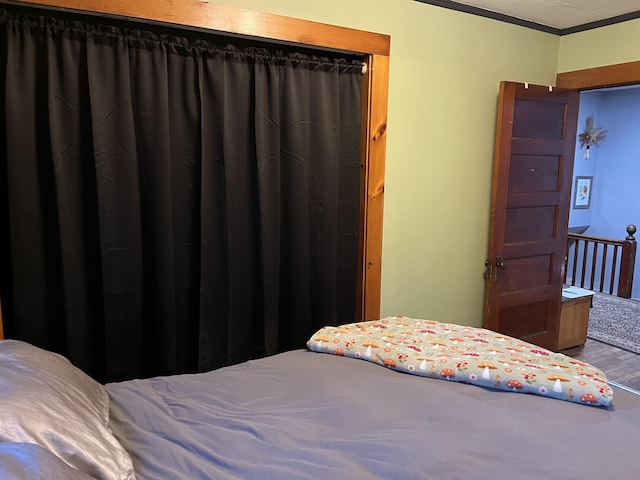 bedroom with hardwood / wood-style floors, a closet, and crown molding