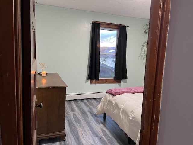 bedroom with baseboard heating and dark hardwood / wood-style floors