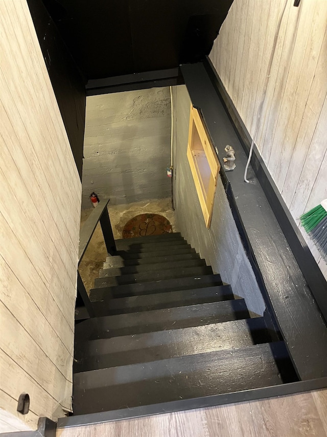 stairway featuring wood walls