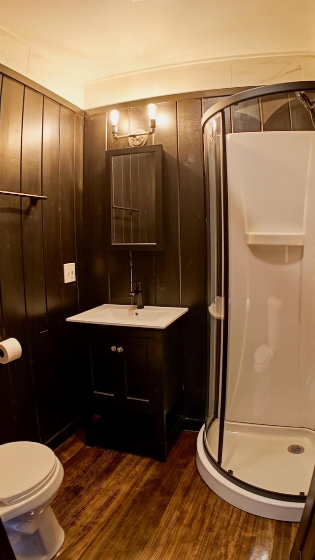 bathroom featuring hardwood / wood-style floors, toilet, walk in shower, and vanity