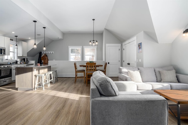 living room featuring a chandelier, light wood-type flooring, and vaulted ceiling