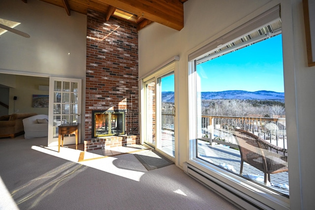 sunroom / solarium featuring a mountain view, beam ceiling, ceiling fan, and a baseboard heating unit