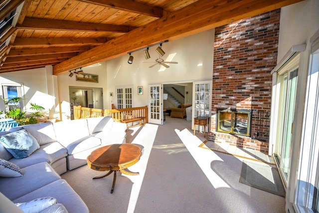 carpeted living room with high vaulted ceiling, ceiling fan, a fireplace, beamed ceiling, and wood ceiling