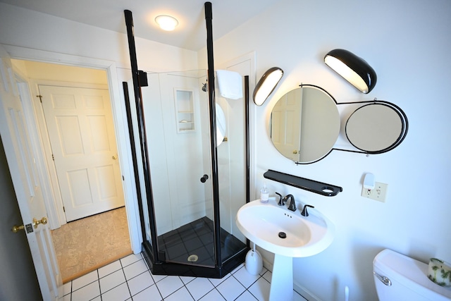 bathroom featuring tile patterned flooring, toilet, and a shower with door