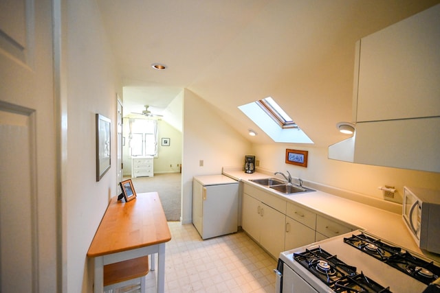 kitchen featuring ceiling fan, sink, refrigerator, white range with gas cooktop, and vaulted ceiling with skylight