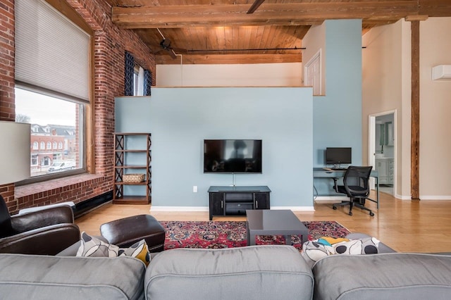 living room featuring a towering ceiling, beam ceiling, light hardwood / wood-style floors, wood ceiling, and brick wall