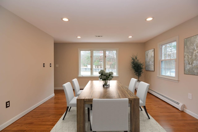 dining space with a baseboard radiator and light hardwood / wood-style flooring