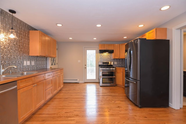 kitchen with sink, light hardwood / wood-style flooring, a baseboard heating unit, decorative light fixtures, and appliances with stainless steel finishes