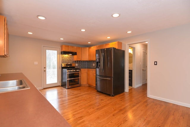 kitchen featuring light brown cabinets, sink, light hardwood / wood-style flooring, decorative backsplash, and stainless steel appliances